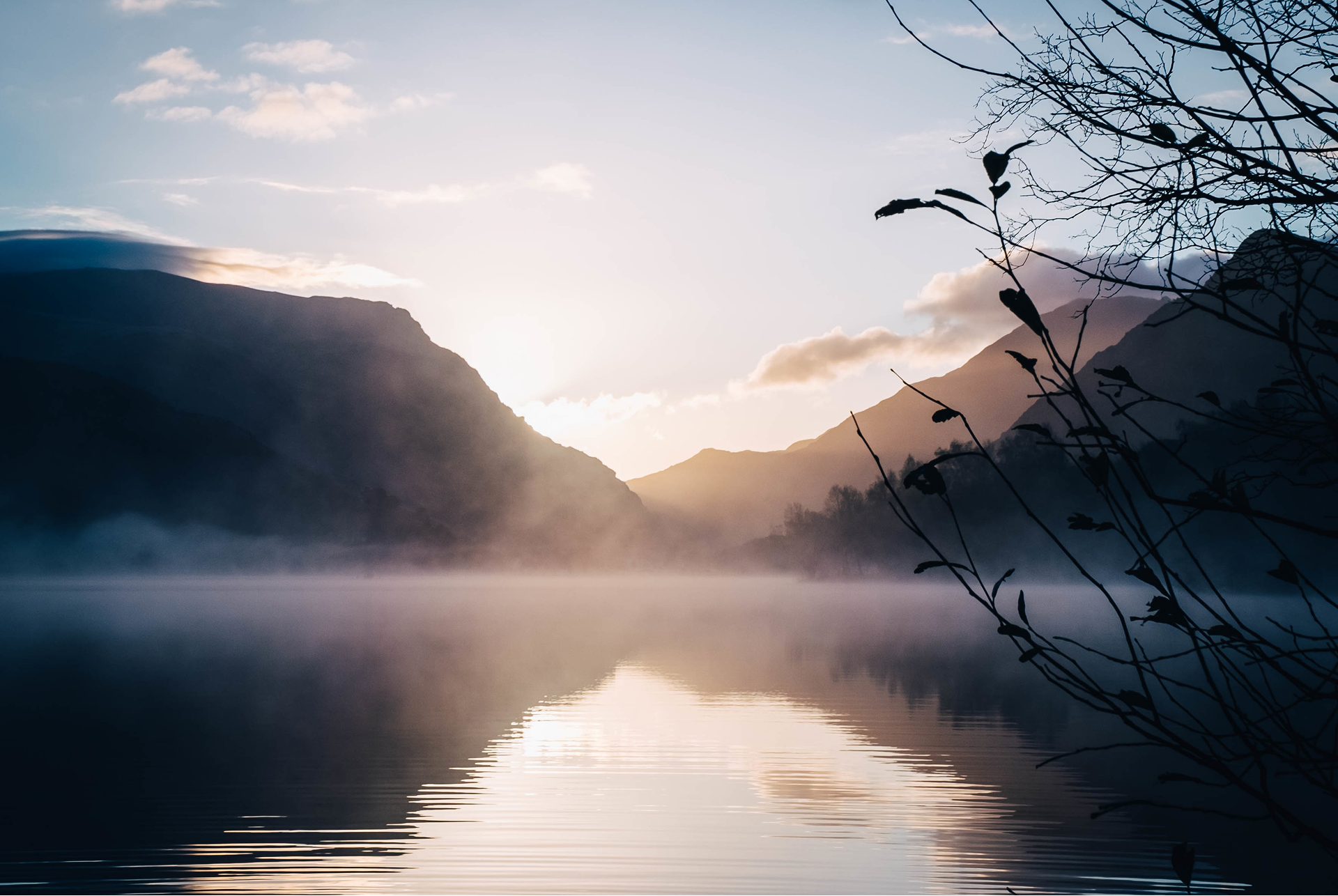 Stiller See am Morgen mit einem Sonnenaufgang und Bergen im Hintergrund als Symbolbild für innere Ruhe und Frieden.