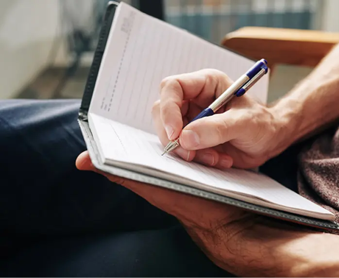 Hand notiert Gedanken in einem Notizheft als Symbol für Reflexion und innere Klärung.